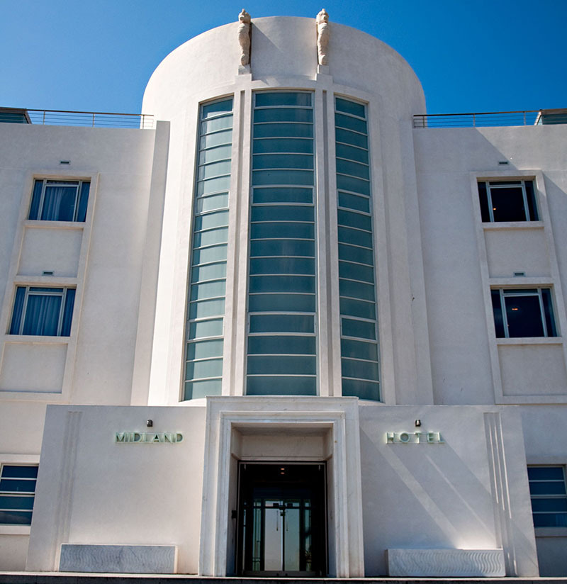 The Midland Hotel in Morecambe, a stunning example of Art Deco architecture, with its white curved facade gleaming against a blue sky.